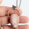 Copper backside of pendant in human hand.