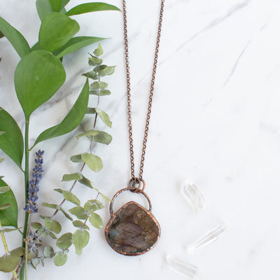 Labradorite and Copper necklace beside green leaves and a lavender sprig.