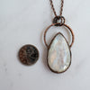 The Rainbow Moonstone pendant is shown beside a Canadian Quarter coin for size comparison.