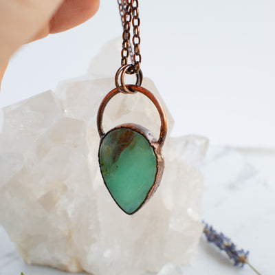 Blue Peruvian Opal and copper necklace shown with the light shining through the pendant.