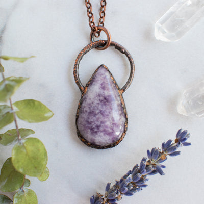 Lepidolite and Copper electroformed necklace shown beside green eucalyptus branch, Quartz crystals and lavender.