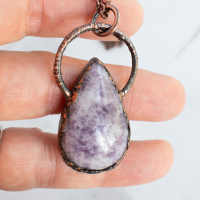 Lilac Lepidolite and Copper electroformed pendant shown in human hand.