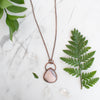 Australian Pink Opal and Copper necklace shown beside greenery and Quartz crystals.