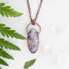 Lepidolite and Copper electroformed necklace shown beside greenery and Quartz crystals.