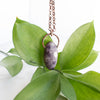 Purple Lepidolite and Copper electroformed necklace shown in front of green leaves,