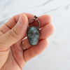 Labradorite and Copper skull necklace shown in human hand.