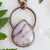 Soothing Pink Australian Opal and copper pendant shown beside green leaves and a Quartz point.