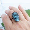 Blue Labradorite and Copper Skull RIng worn on a hand.