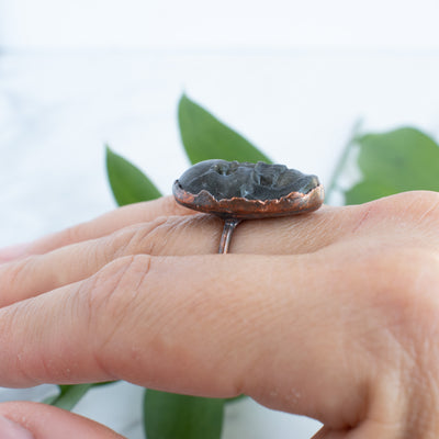 Side view of a Labradorite and Copper Skull RIng worn on a hand.