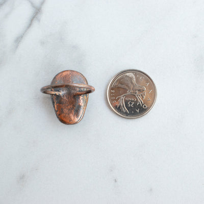 Back side of a Labradorite and Copper Electroformed Skull Ring beside a Canadian Quarter coin.