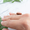 The side view of a Peach Moonstone and Copper ring worn on a hand.