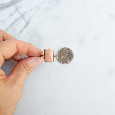 A Peach Moonstone and Copper ring shown beside a Canadian Quarter coin.