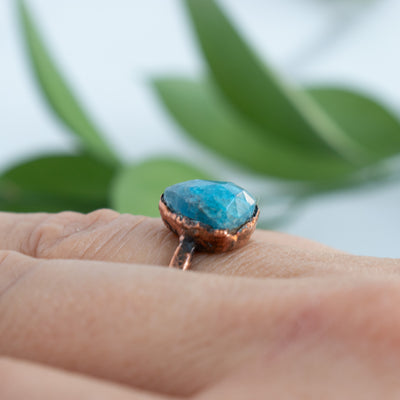 Side view of the Blue Apatite and Copper ring shown worn on a woman's hand.