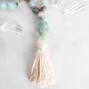 Blue Amazonite Guru bead with cream silk tassel arranged beside Quartz crystals.