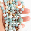 Soothing tones of blue, cream and brown Amazonite Mala necklace held in a woman's hand.