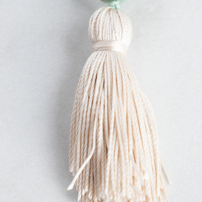 Handtied cream Silk tassel arranged on a white background.