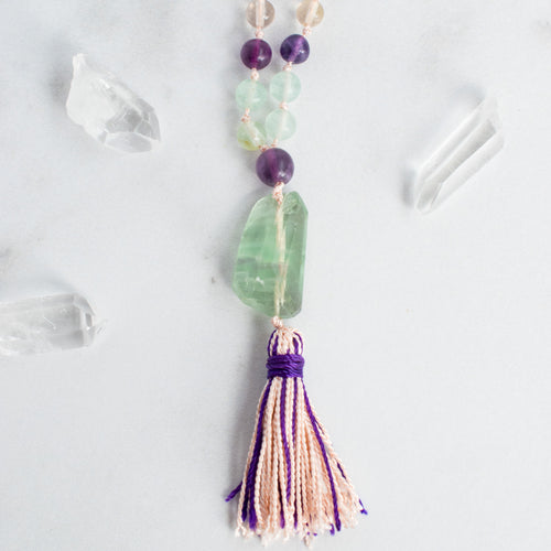 Beautiful tones of purple, green and clear Rainbow Flourite accent the light pink and purple handmade tassel in this Mala necklace.