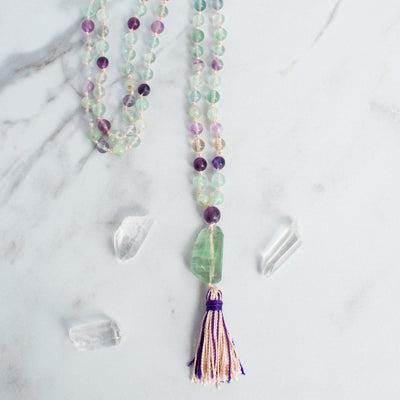 Tones of purple, green and clear Rainbow Flourite beads shine in this hand knotted Mala necklace with Rainbow Flourite Guru bead and handmade nylon tassel.