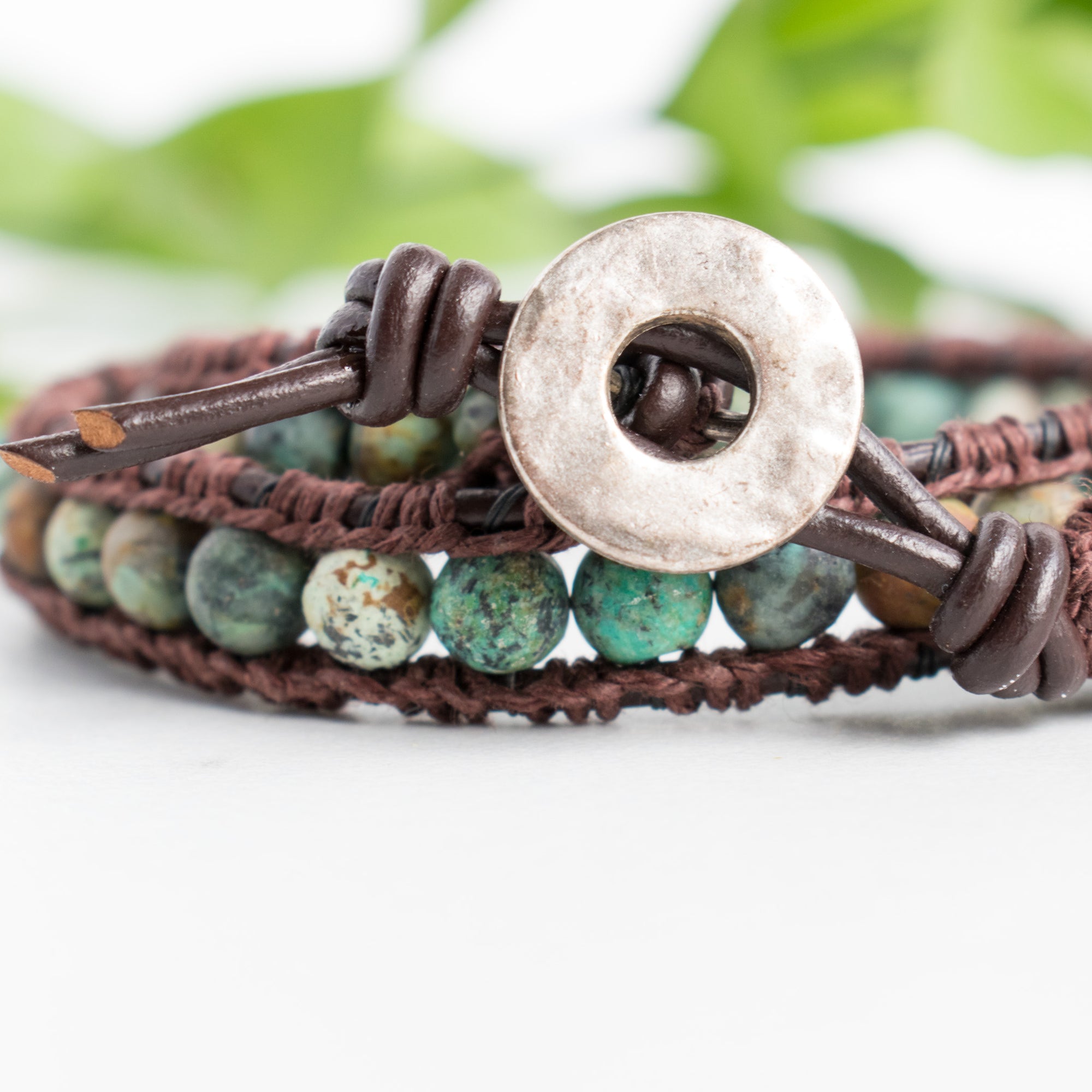 Close up photo shows the details of the African Turquoise beads and silver toned button in this leather and hemp wrap bracelet.