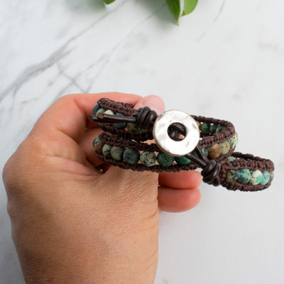 African Turquoise and leather wrap bracelet held in a woman's hand.