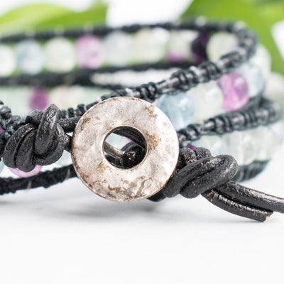 Close up showing the detailing on the silver toned button closure of the woman's wrap bracelet.