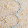 Light blue Aquamarine and Silver plated hoop earrings shown on a wooden background.