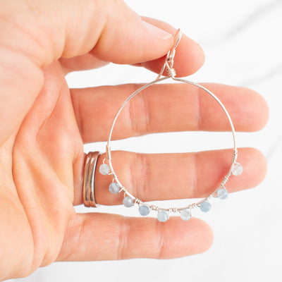 Icy blue Aquamarine and Silver plated Hoop earring shown held in a woman's hand.