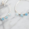 Light reflects off the facets on these blue Aquamarine silver plated hoop earrings.