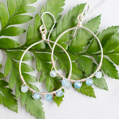 Pale icy blue Aquamarine and Silver plated hoop earrings shown on a green fern frond.