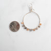 Moonstone and silver plated hoop earring shown next to a Canadian Quarter for size reference.