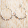 Peach and grey Moonstone hoop earrings shown against a wooden background.