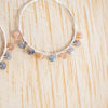 Moonstone and silver plated wire wrapped hoop earrings on a wooden background.