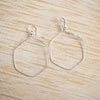 Wire wrapped Silver plated hexagonal earrings on a wooden background.