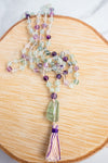 Hand-knotted Rainbow Flourite Mala necklace arranged on a wooden background.