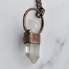 A Clear Quartz point is encircled in antique copper. Light reflects off the backside of the pendant revealing the texture.