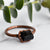A Black Tourmaline ring is set in antique copper in front of green eucalyptus leaves.