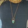 A woman in a black shirt wears a Labradorite coffin pendant featuring flashes of blue, green yellow and pinky-purple. A rainbow moonstone oval accents the top of the copper bail, and hangs on a pure copper rolo chain.