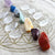 Red, yellow, green, blue and purple crystals are laid in a line, along with Quartz points all on top of a Flower of Life grid cloth.